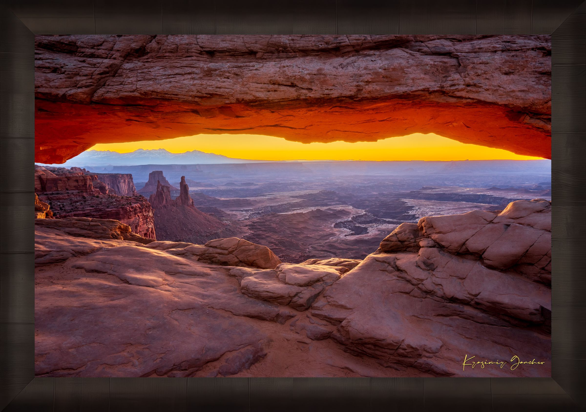 Mesa Arch in Canyonlands National Park framing a sunrise horizon under hazy skies, with golden rays illuminating rock formations. #Finish_Roma Dark Ash Frame