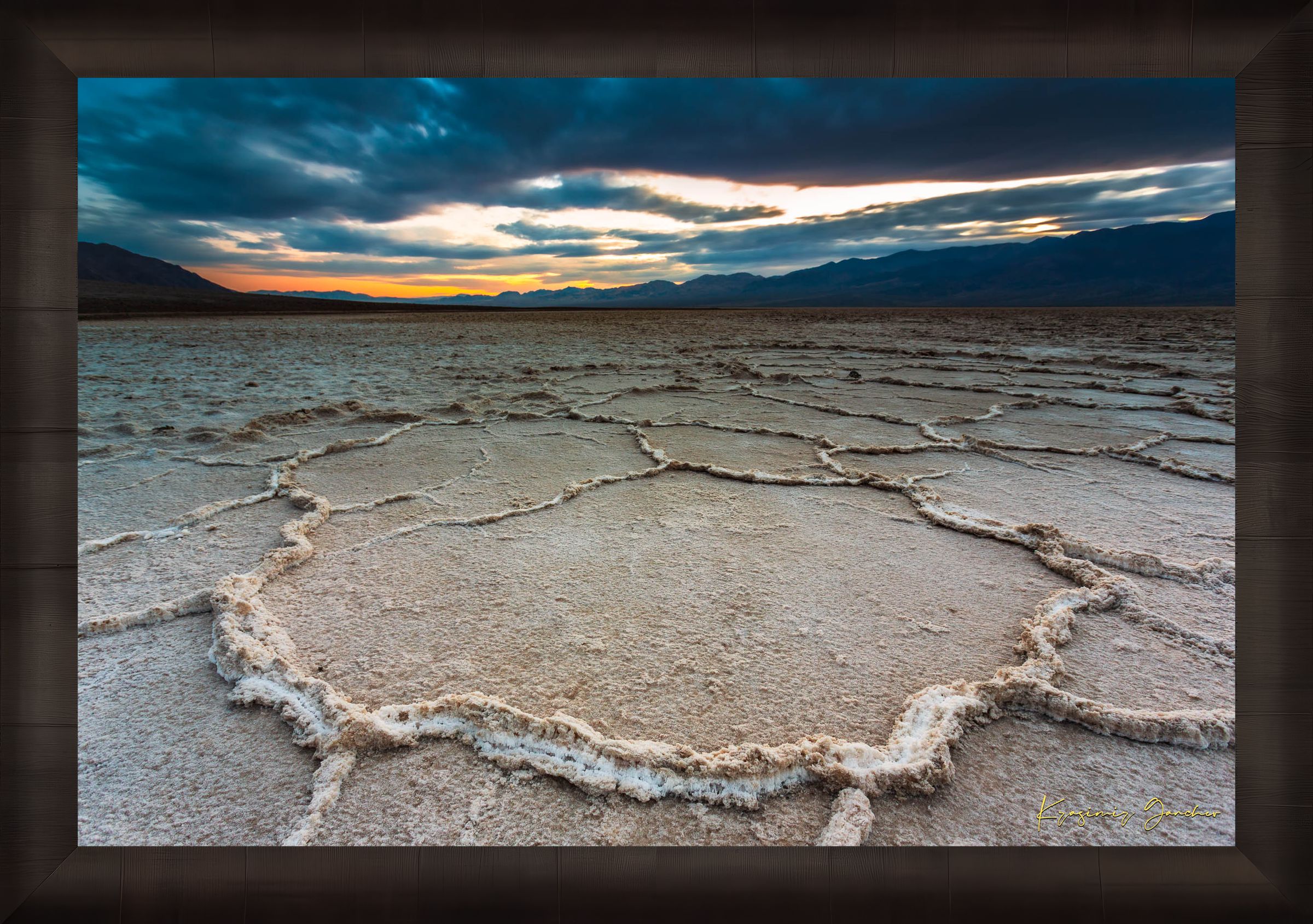 Expansive desert salt flat of Badwater Basin beneath a sky filled with storm clouds and setting sun in Death Valley. #Finish_Roma Dark Ash Frame