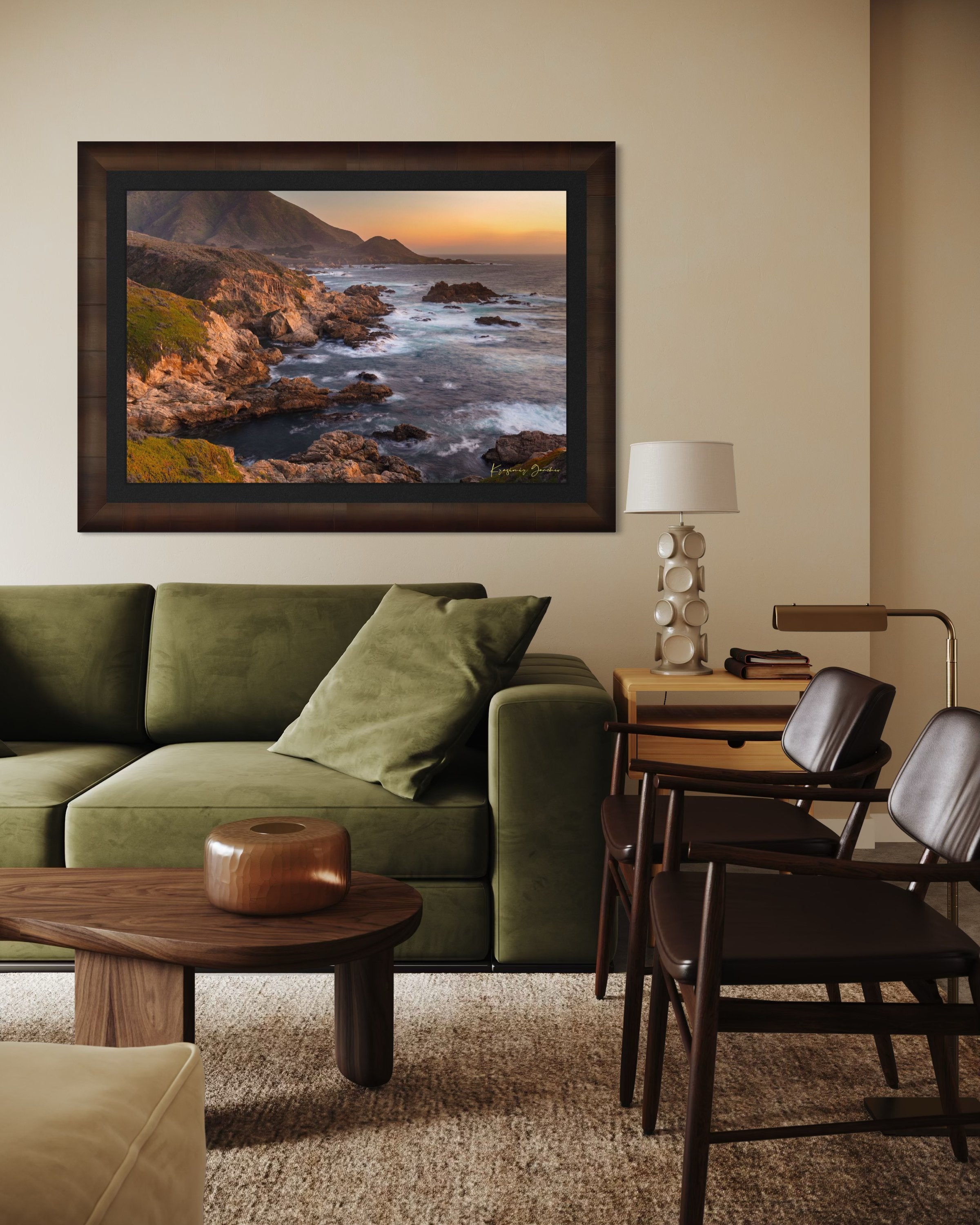 Rugged coastline of Big Sur featuring dark boulder formations, green slopes, ocean waves, and soft sunset glow across land and sea. #Finish_Roma Cigar Leaf Frame & Dark Liner