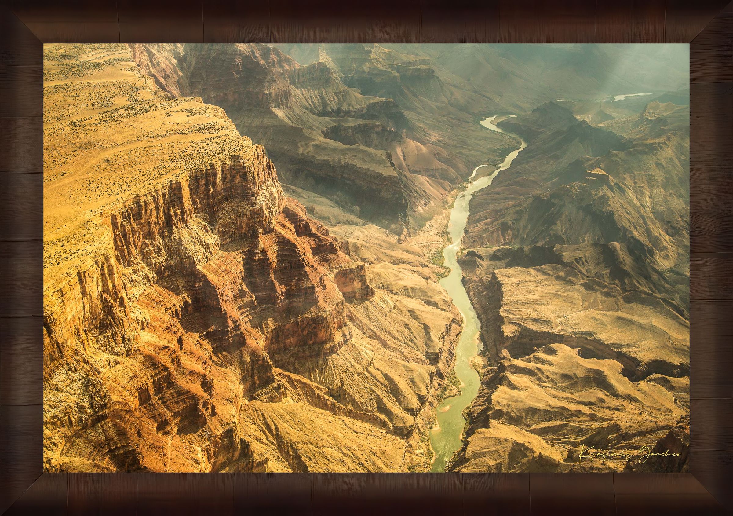 Colorado River traversing the Grand Canyon chasm in daylight, visible geological formations shrouded in haze. #Finish_Roma Cigar Leaf Frame