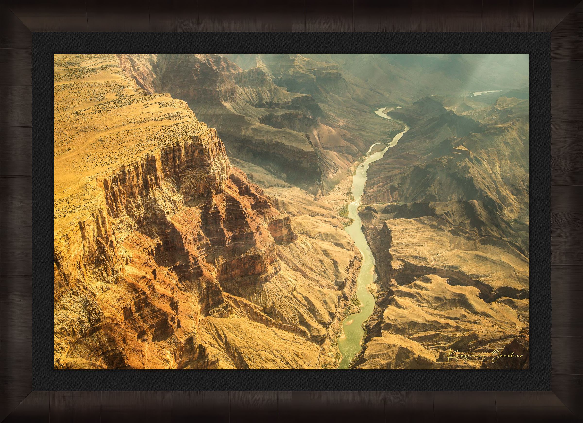 Colorado River traversing the Grand Canyon chasm in daylight, visible geological formations shrouded in haze. #Finish_Roma Dark Ash Frame & Dark Liner