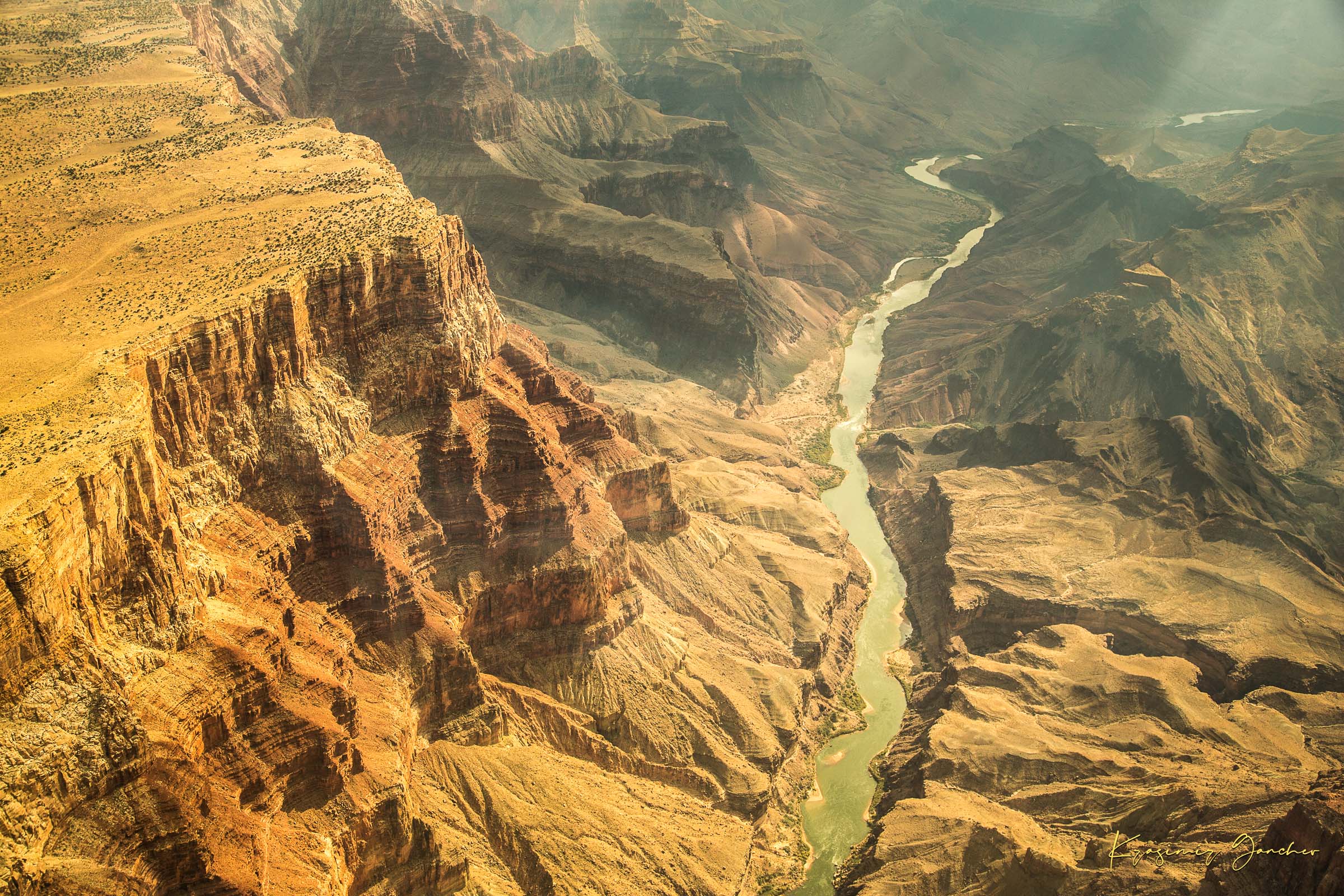 Colorado River traversing the Grand Canyon chasm in daylight, visible geological formations shrouded in haze. #Finish_Acrylic Recess