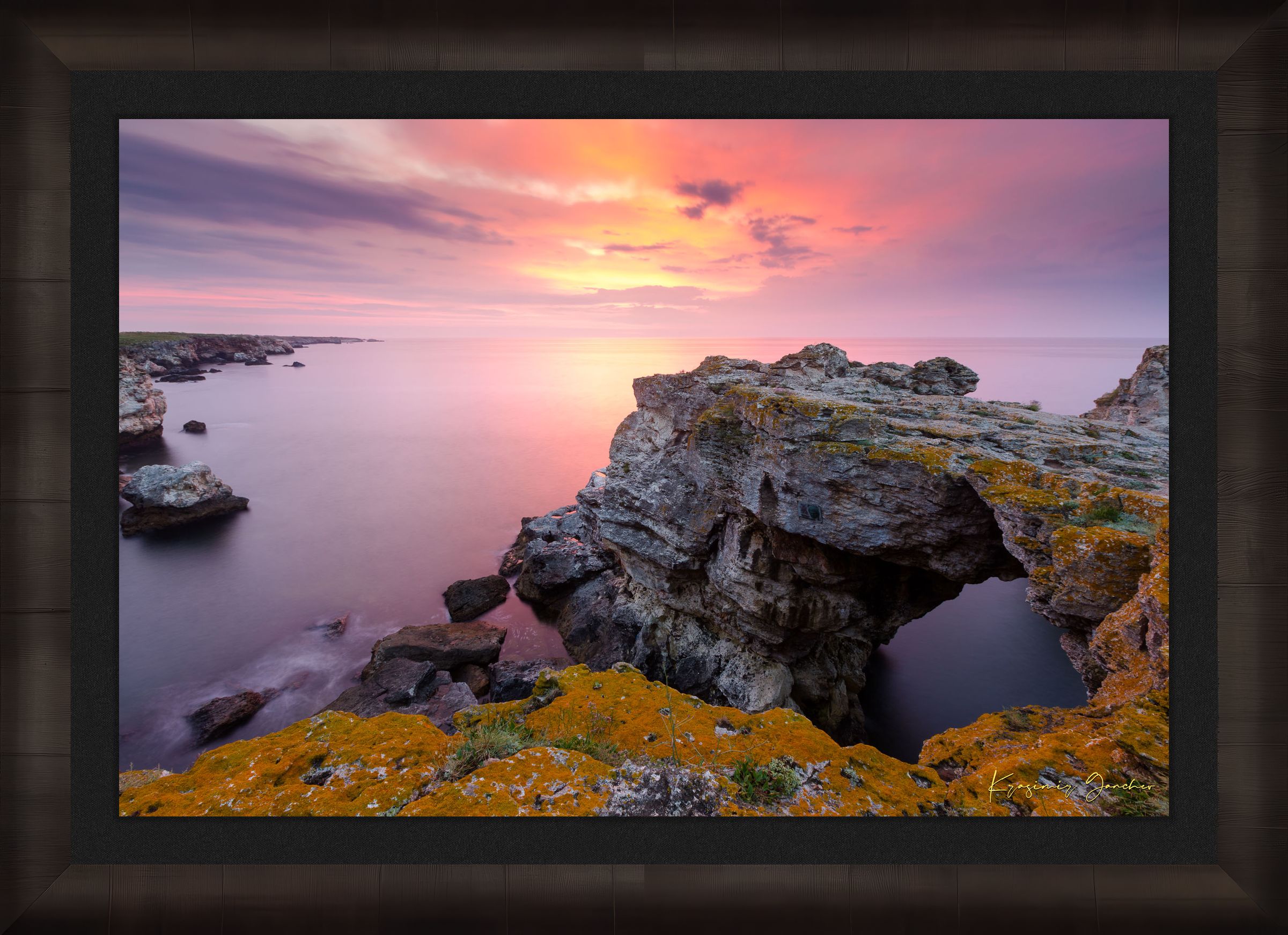 The natural arch formation of the Tyulenovo Arch at dawn in Tyulenovo, Bulgaria, lit by sunrise and surrounded by vegetation. #Finish_Roma Dark Ash Frame & Dark Liner