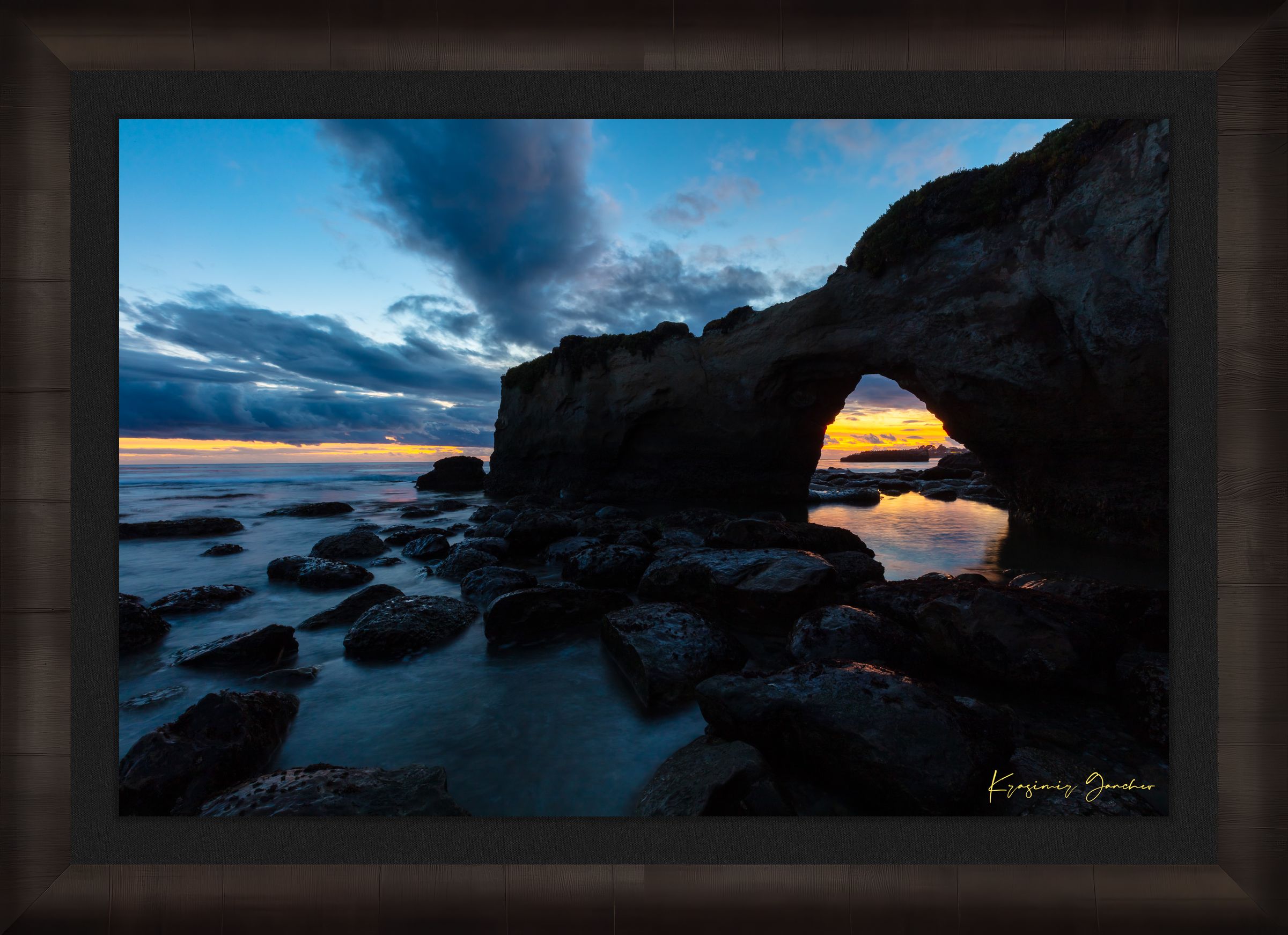 Natural rock arch framing sunset over the Pacific Ocean with waves moving around boulders at Santa Cruz coastline. #Finish_Roma Dark Ash Frame & Dark Liner