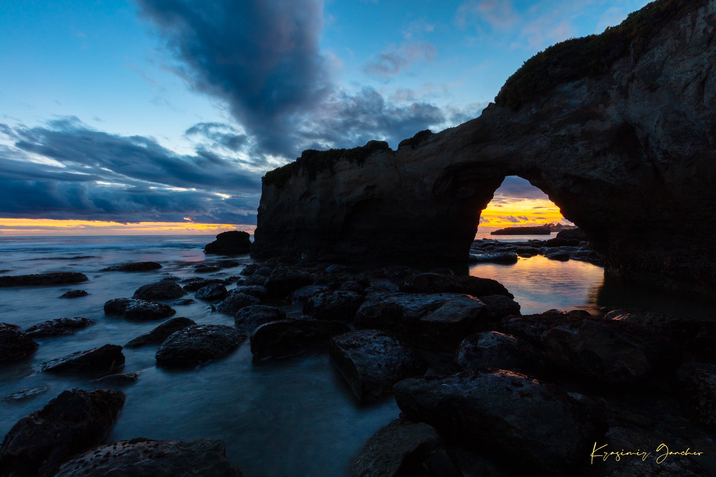 Natural rock arch framing sunset over the Pacific Ocean with waves moving around boulders at Santa Cruz coastline. #Finish_Acrylic Recess
