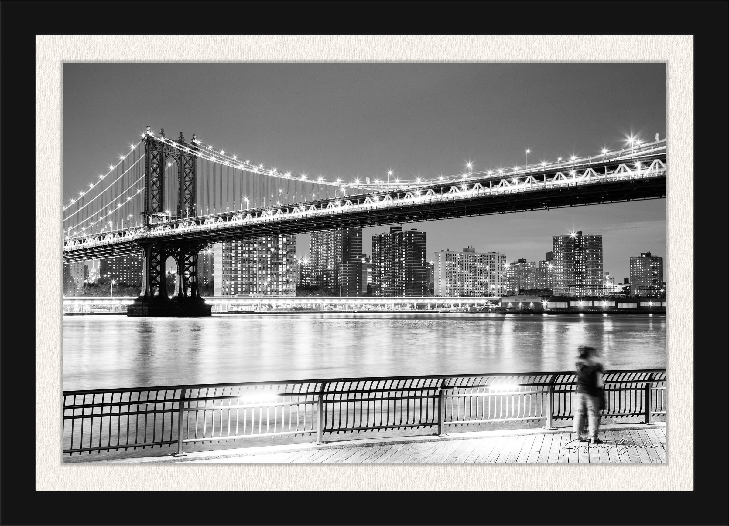 Monochrome Brooklyn Bridge at night across the Manhattan estuary, illuminated by city lights. #Finish_Roma Satin Black Frame & Bright Liner