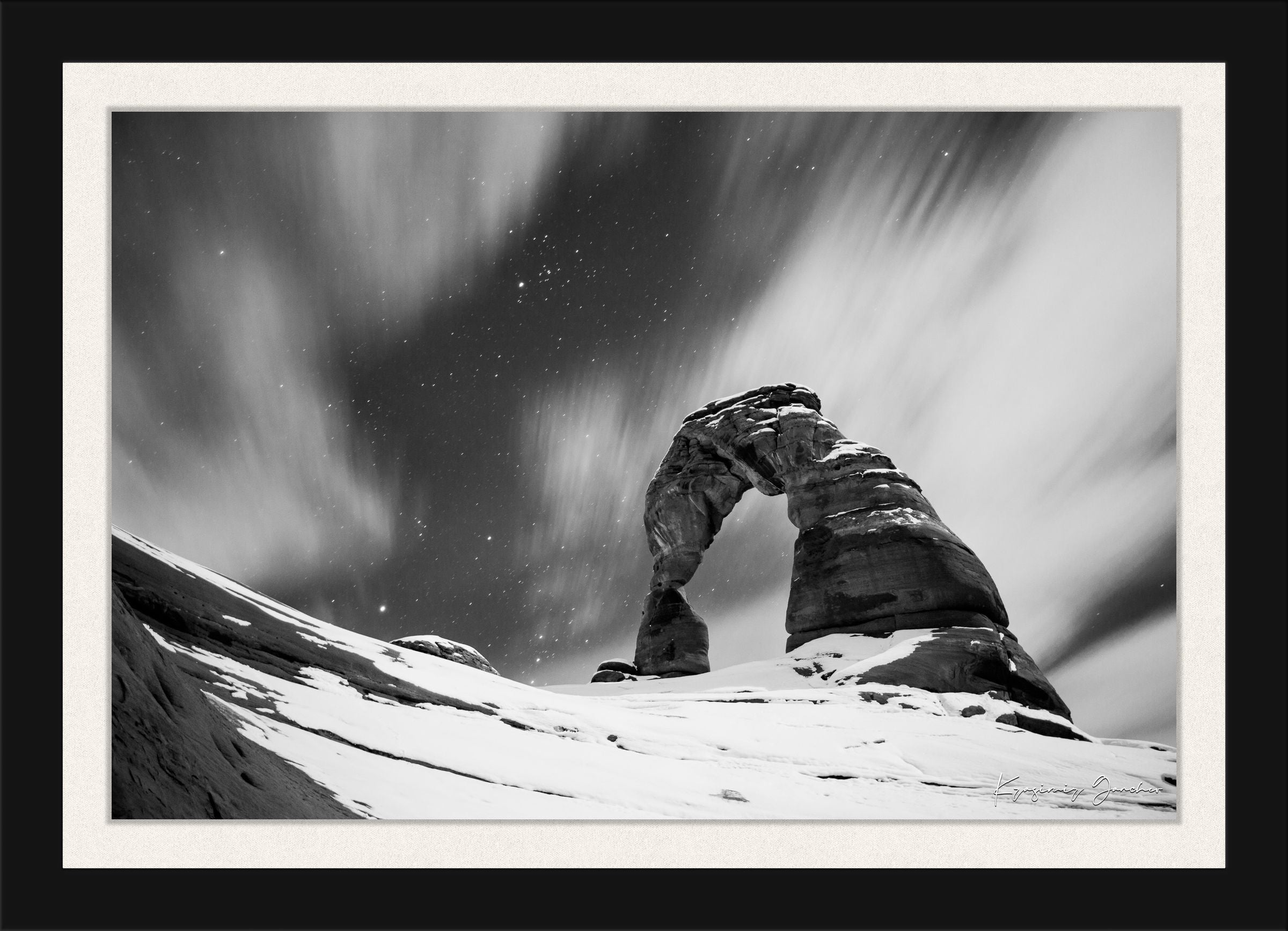 Silhouette of Delicate Arch against a star-filled night sky in Utah's Arches National Park, featuring cloud trails and snow cover. #Finish_Roma Satin Black Frame & Bright Liner