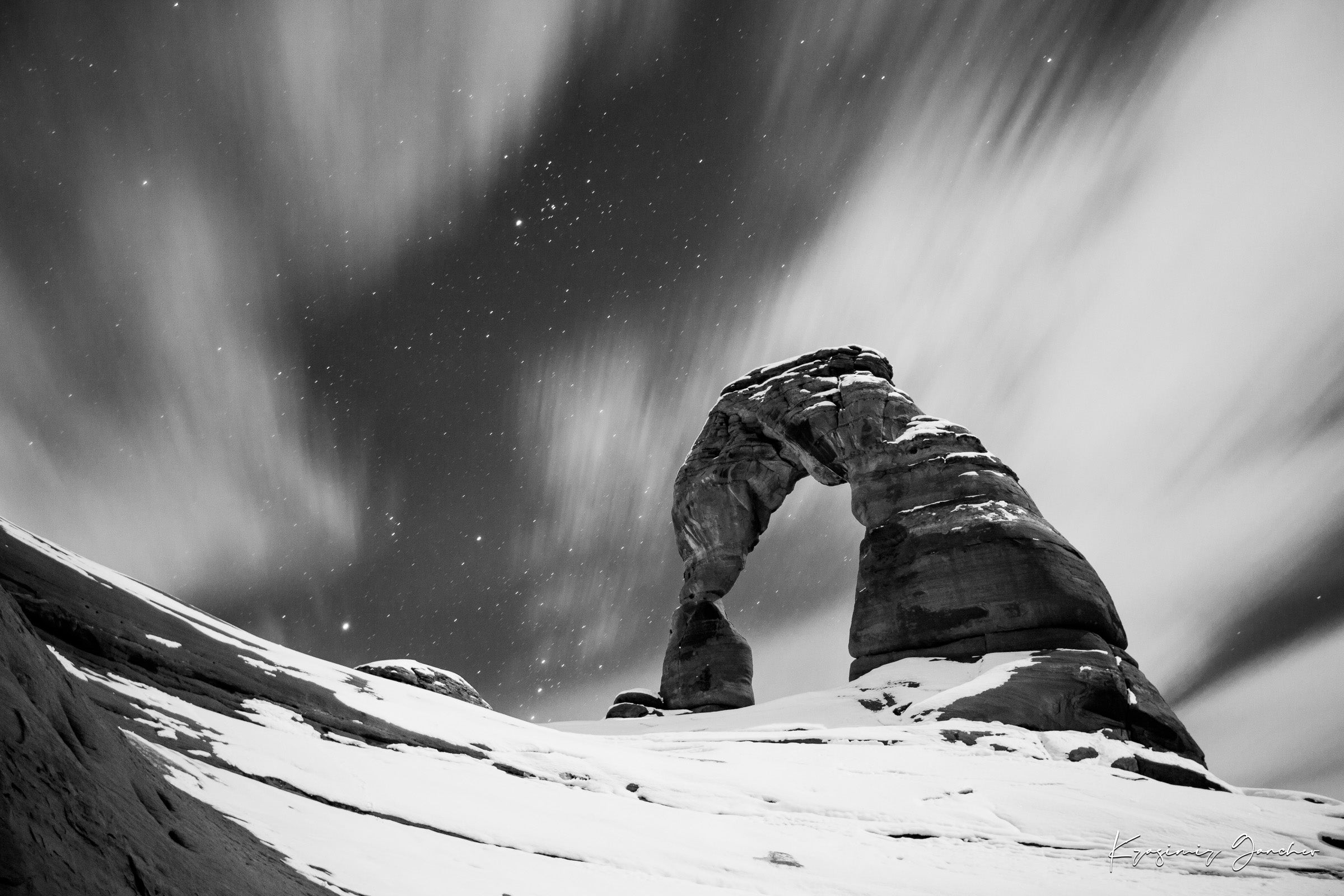 Silhouette of Delicate Arch against a star-filled night sky in Utah's Arches National Park, featuring cloud trails and snow cover. #Finish_Acrylic Recess