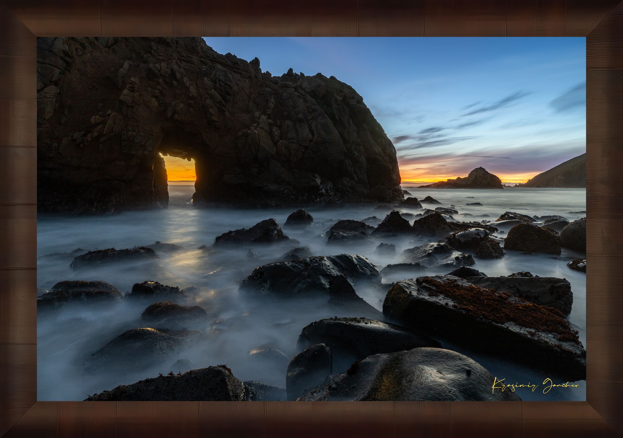 Natural arch structure with boulders and sea stack near Big Sur, California, lit by intense sunset rays through a stone opening. #Finish_Roma Cigar Leaf Frame