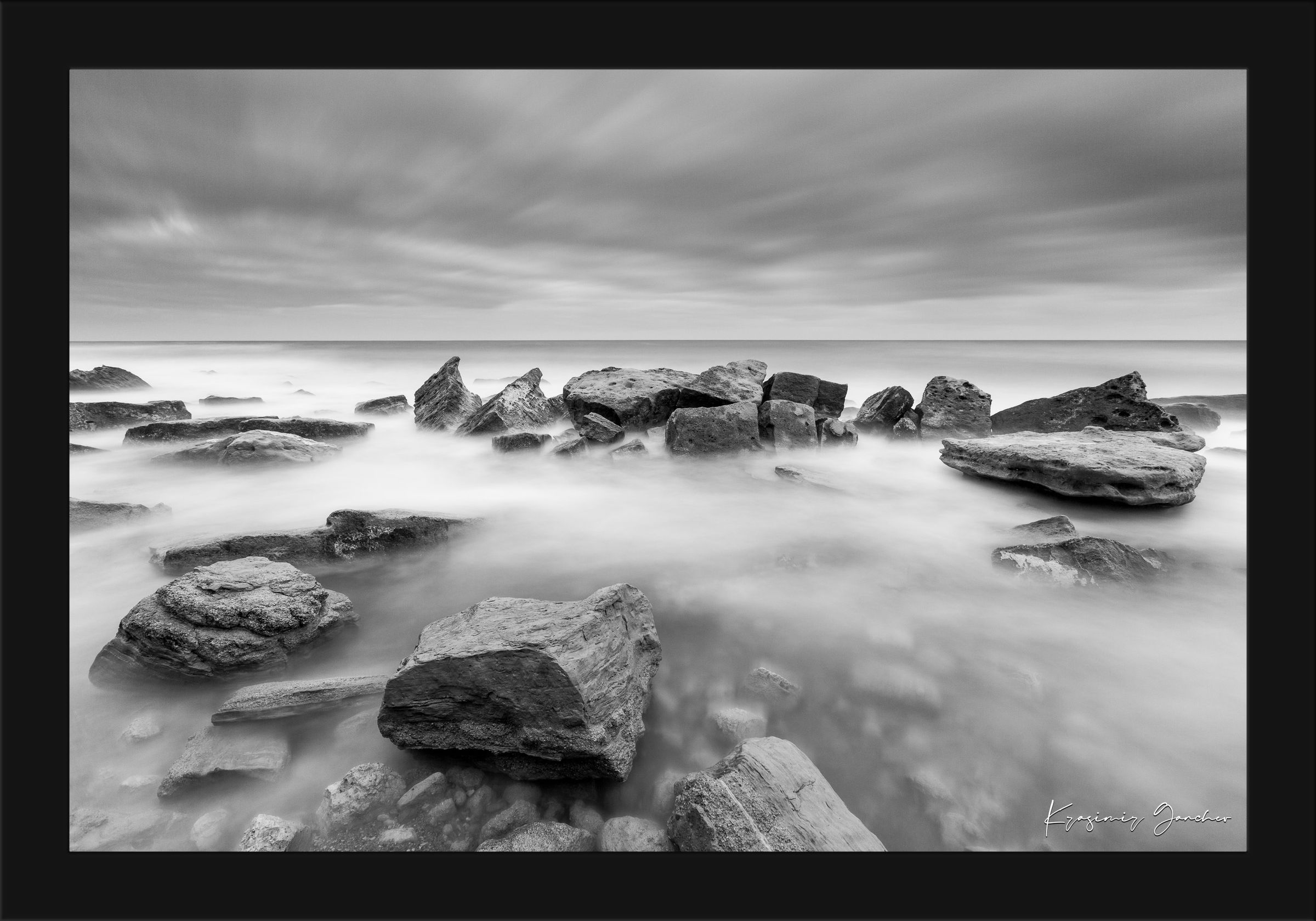 Coastal rock and sand landscape at Fichoza, Bulgaria captured in monochrome during daylight under cloudy skies. #Finish_Roma Satin Black Frame