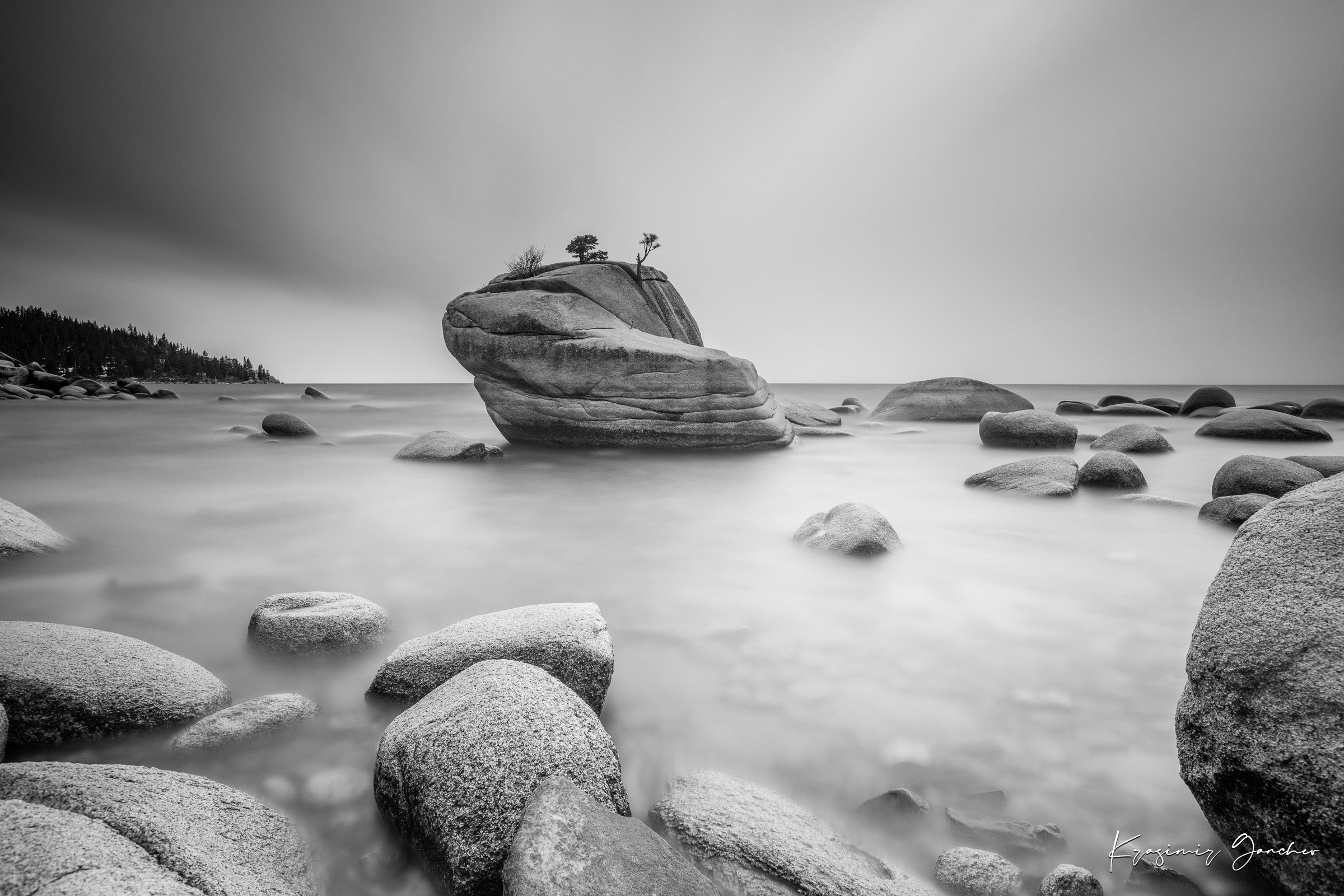 Large boulder named Bonsai Rock in Lake Tahoe surrounded by still, reflective waters under daytime light. #Finish_Acrylic Recess