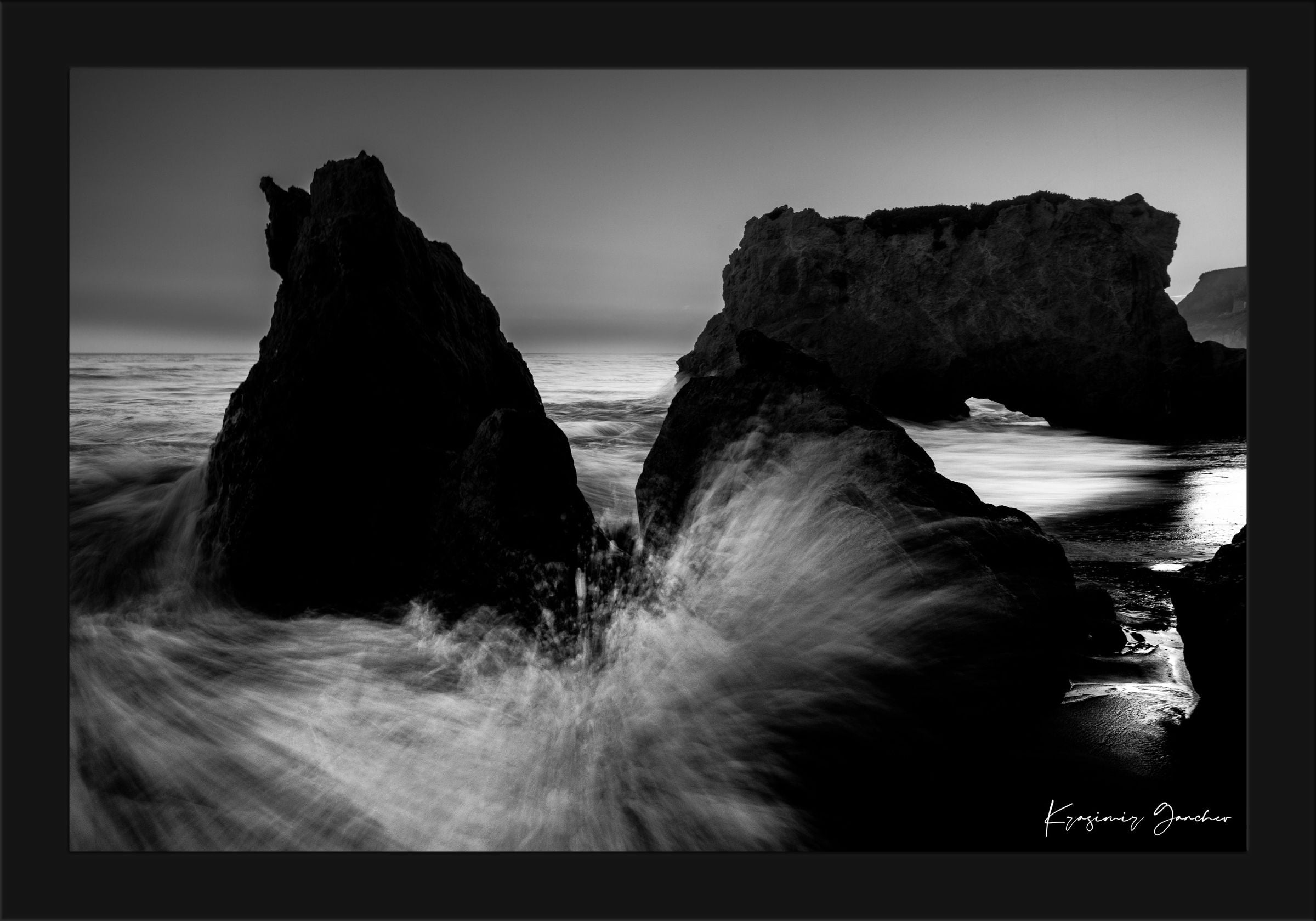 Rock arch formation along the coastal ocean at El Matador Beach, Malibu, California, with crashing waves and dusky atmosphere. #Finish_Roma Satin Black Frame