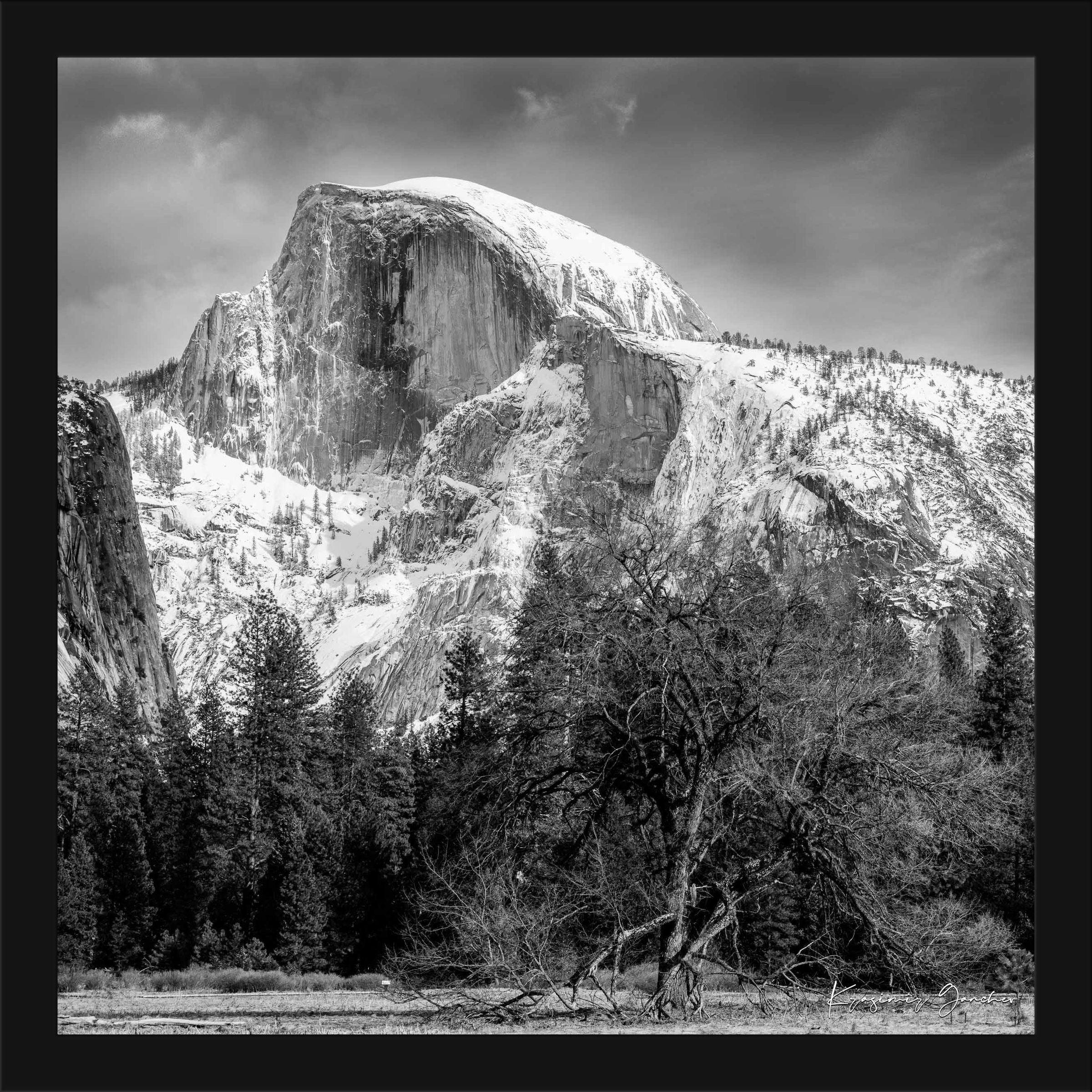 Monolithic Half Dome stands in stark contrast against a shadowed foreground amid clouds and fresh snow in Yosemite National Park. #Finish_Roma Satin Black Frame