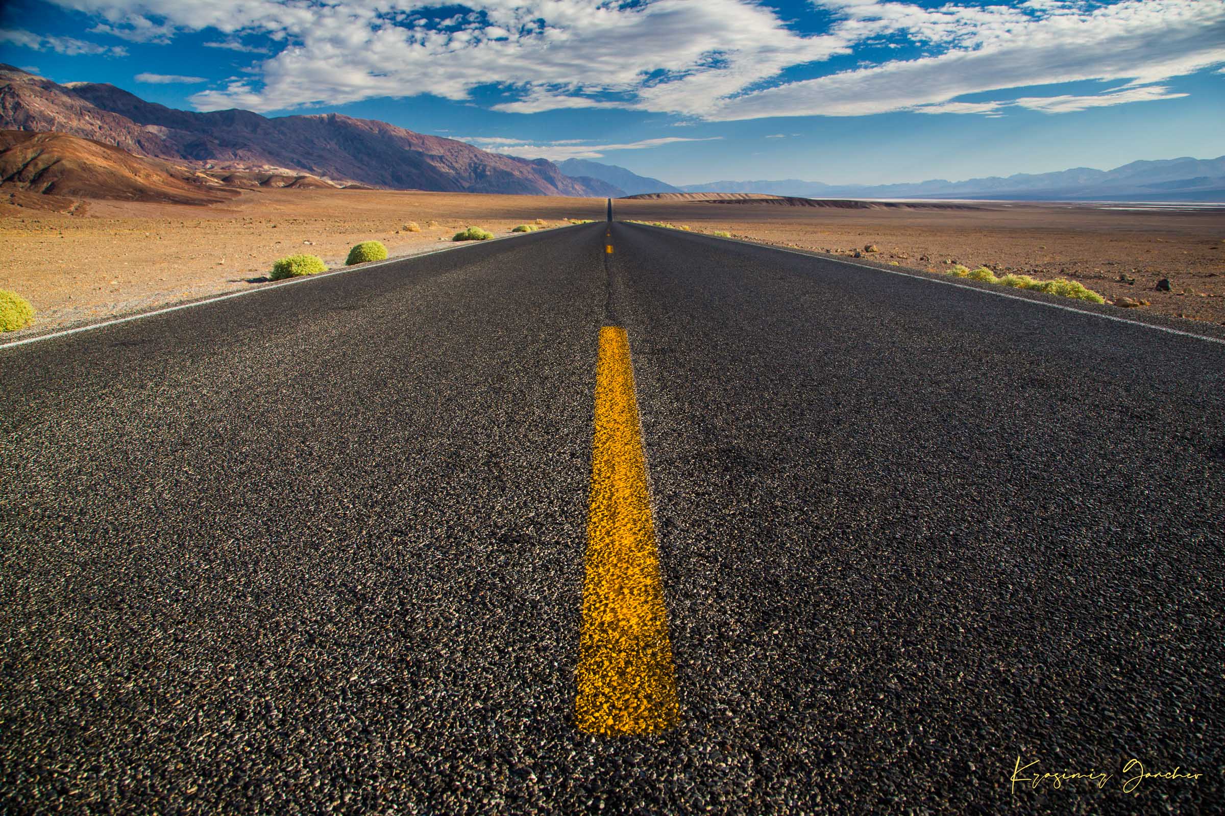 Straight desert road stretching into an open landscape of arid terrain in Death Valley National Park under overcast skies. #Finish_Acrylic Recess