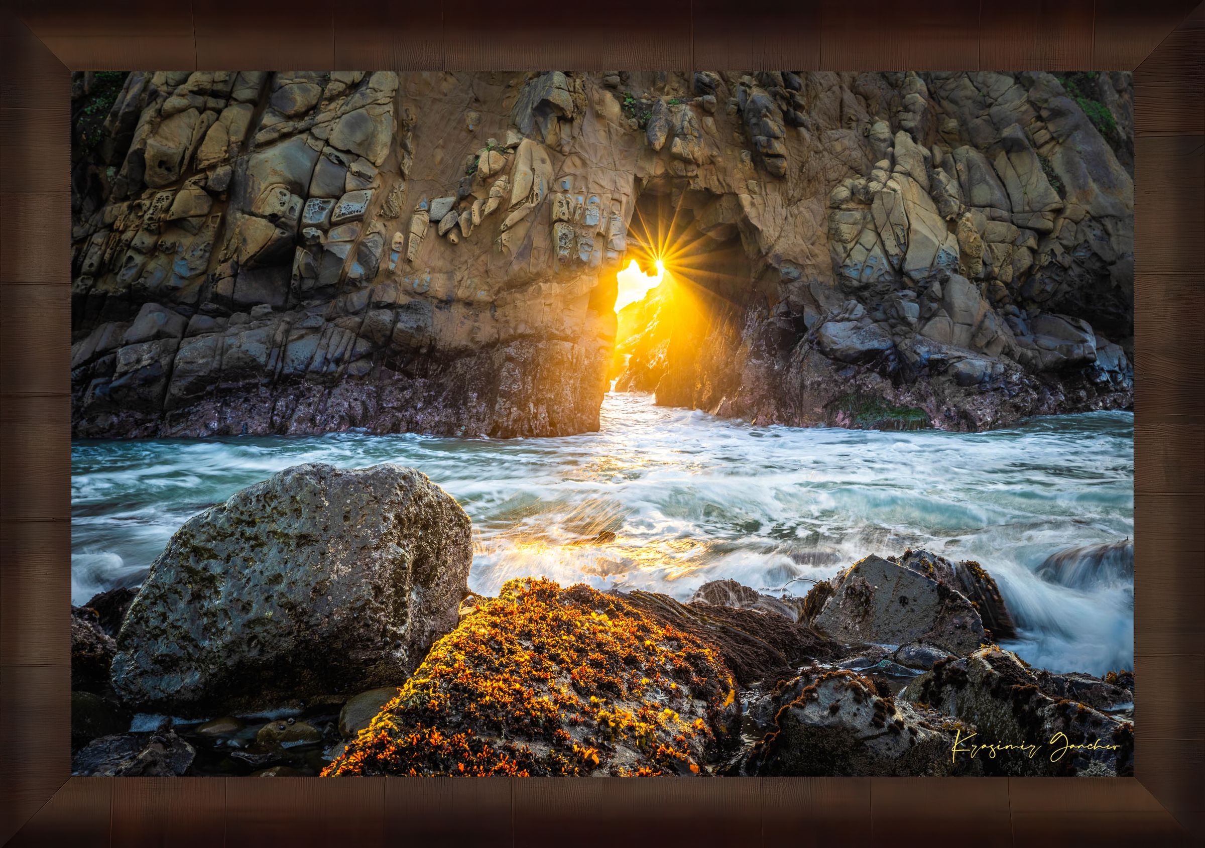 Golden-hour photograph of a coastal arch formed by erosion at Big Sur's rugged shoreline, featuring boulders and open sea. #Finish_Roma Cigar Leaf Frame