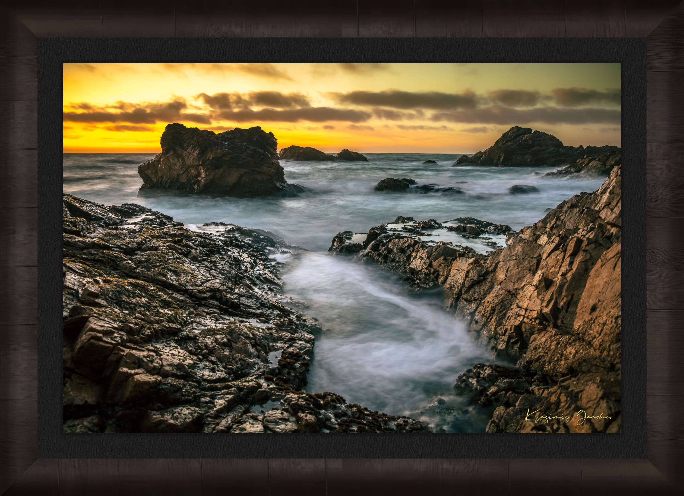 Jagged rocky cliffs along the Big Sur coast with rhythmic wave action, open ocean mist, clouds above, illuminated by late afternoon sunlight. #Finish_Roma Dark Ash Frame & Dark Liner