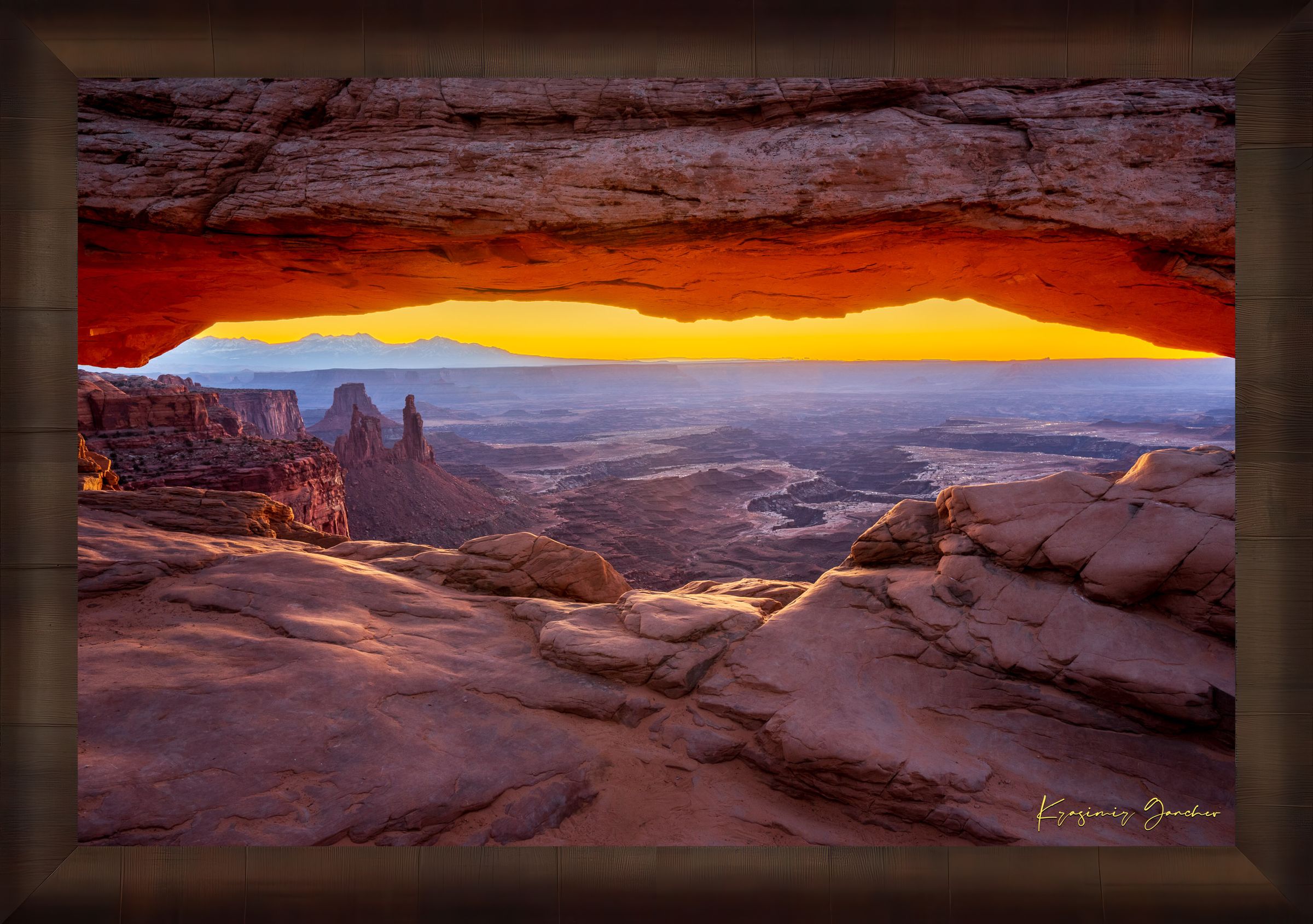 Mesa Arch in Canyonlands National Park framing a sunrise horizon under hazy skies, with golden rays illuminating rock formations. #Finish_Roma Cigar Leaf Frame