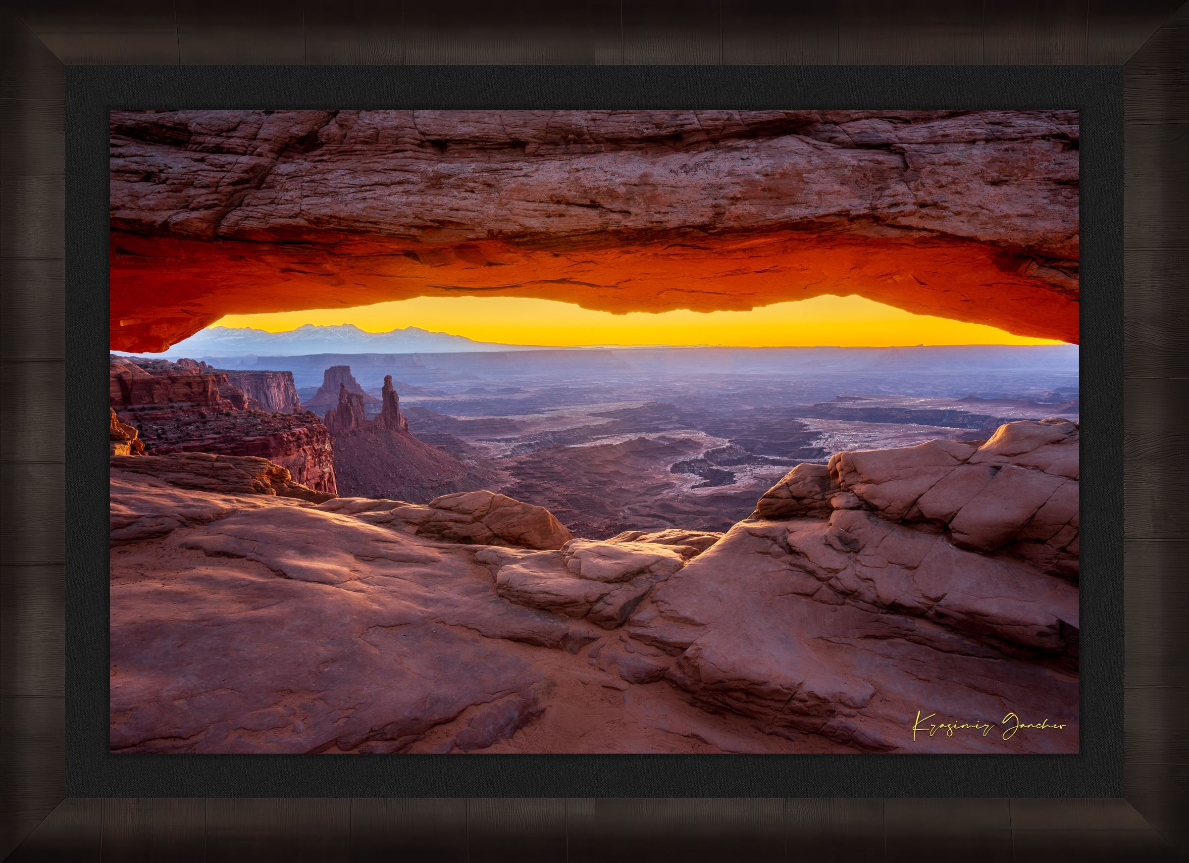 Mesa Arch in Canyonlands National Park framing a sunrise horizon under hazy skies, with golden rays illuminating rock formations. #Finish_Roma Dark Ash Frame & Dark Liner