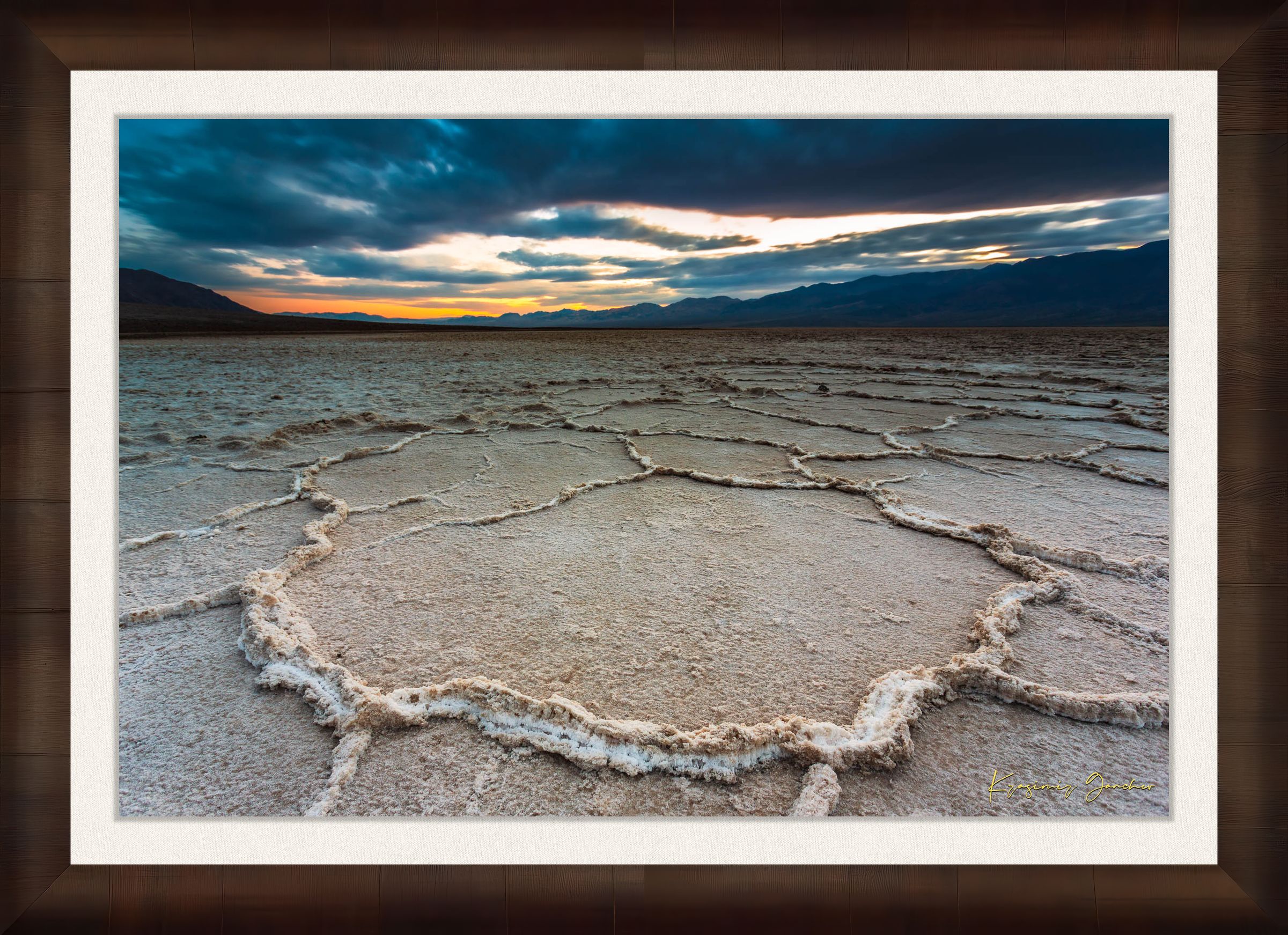 Expansive desert salt flat of Badwater Basin beneath a sky filled with storm clouds and setting sun in Death Valley. #Finish_Roma Cigar Leaf Frame & Bright Liner