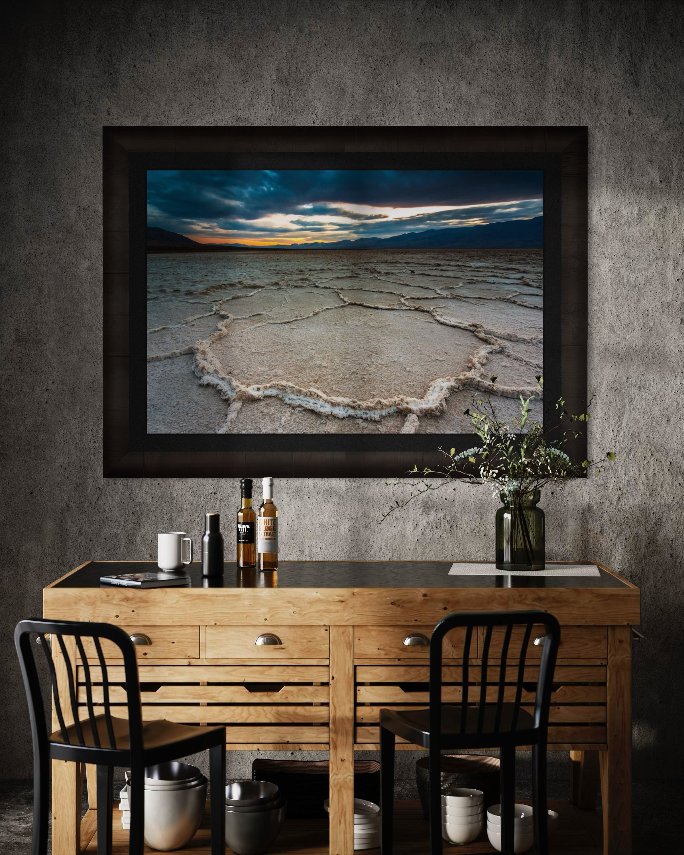 Expansive desert salt flat of Badwater Basin beneath a sky filled with storm clouds and setting sun in Death Valley. #Finish_Roma Dark Ash Frame & Dark Liner