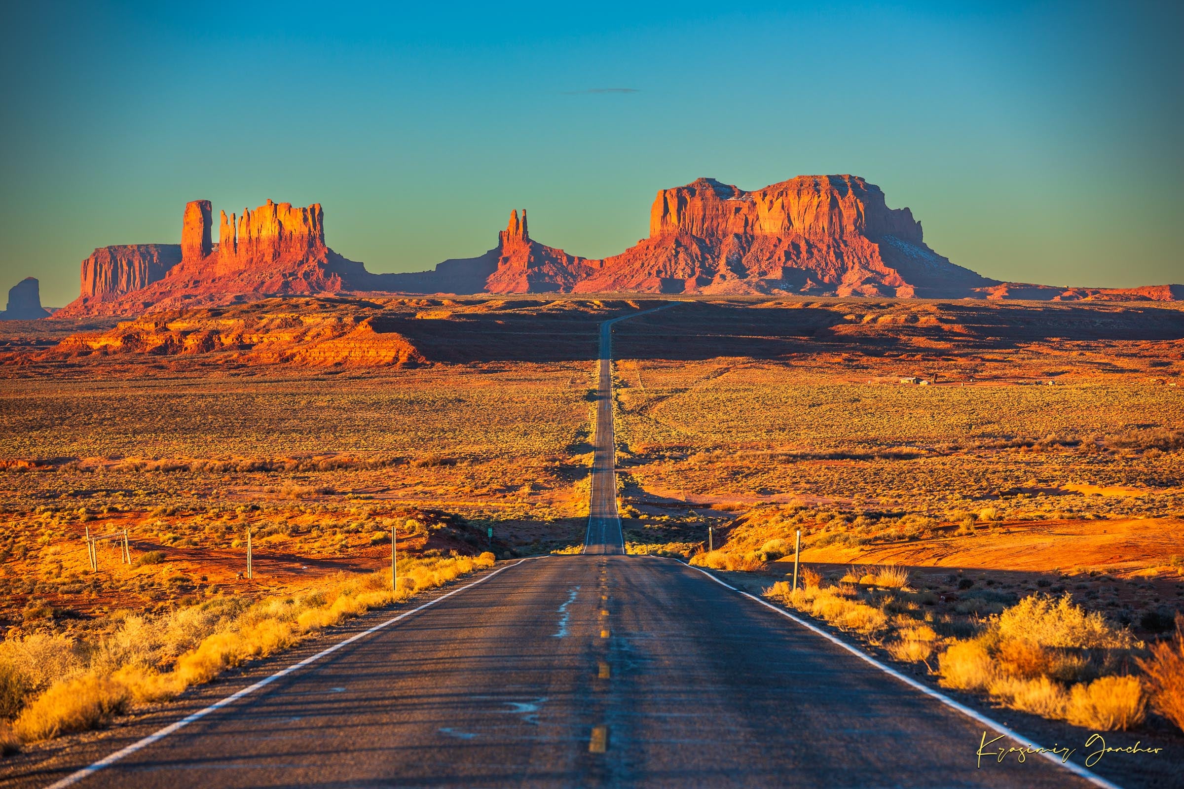 A winding road leads toward distant mesas under a hazy sky in Monument Valley, bathed in warm daylight and soft morning light. #Finish_Acrylic Recess