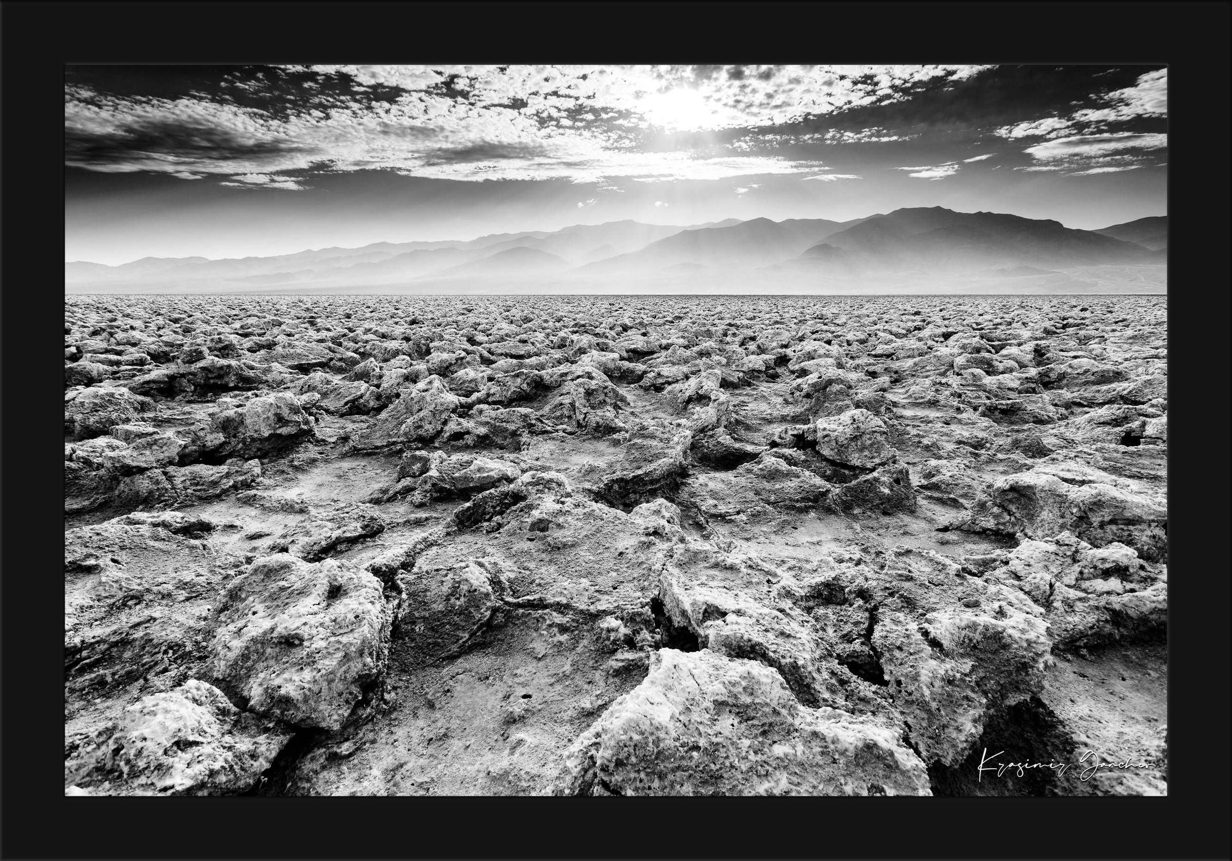 Textured salt pan terrain at Devil's Golf Course in Death Valley National Park under daytime light. #Finish_Roma Satin Black Frame