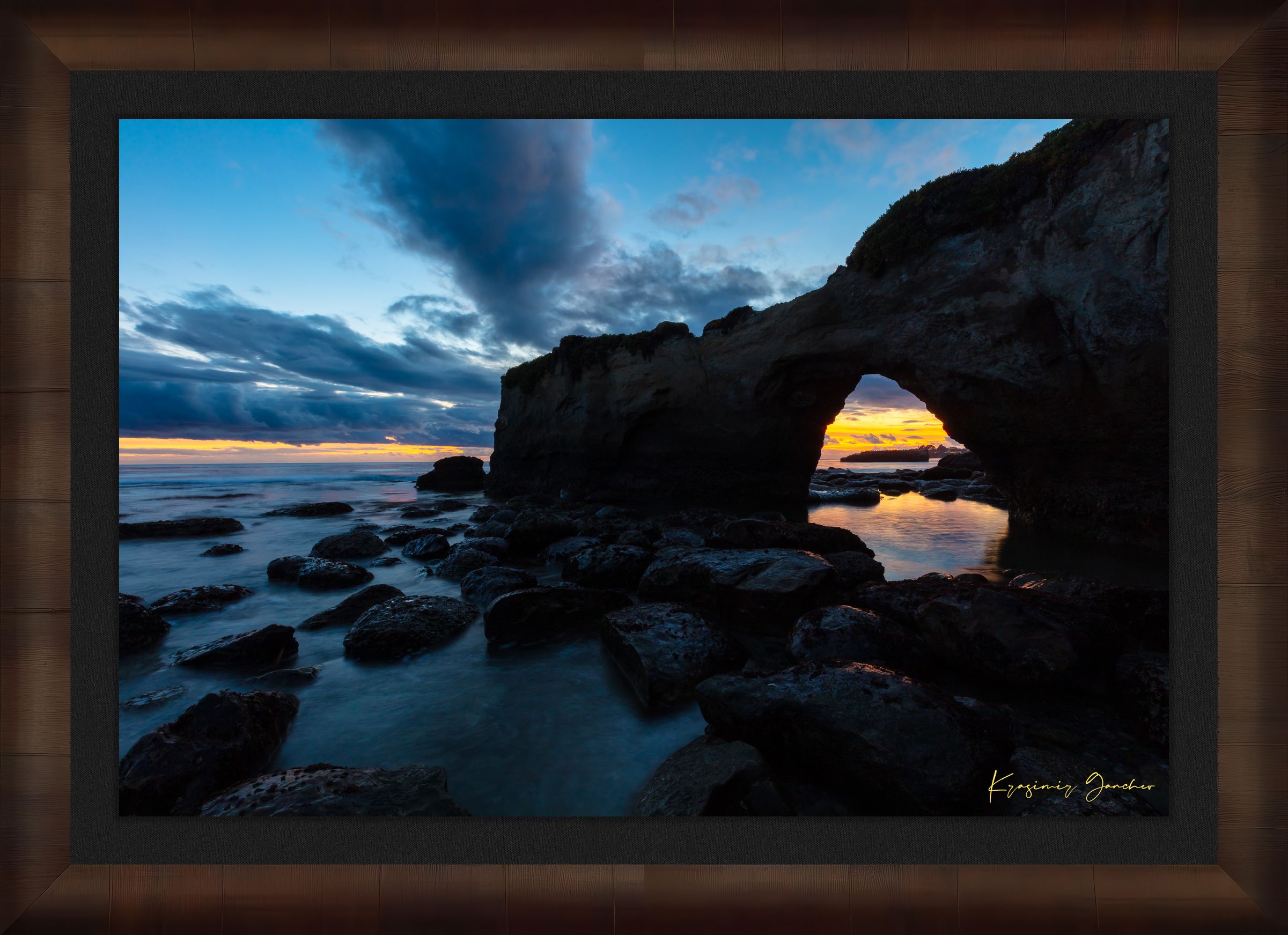 Natural rock arch framing sunset over the Pacific Ocean with waves moving around boulders at Santa Cruz coastline. #Finish_Roma Cigar Leaf Frame & Dark Liner