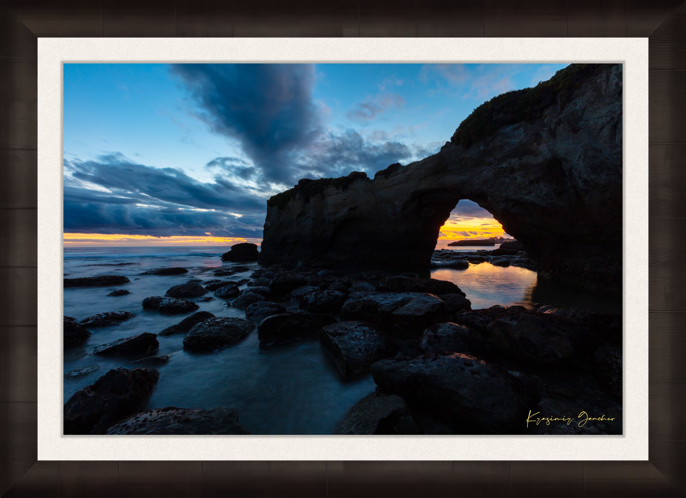 Natural rock arch framing sunset over the Pacific Ocean with waves moving around boulders at Santa Cruz coastline. #Finish_Roma Dark Ash Frame & Bright Liner