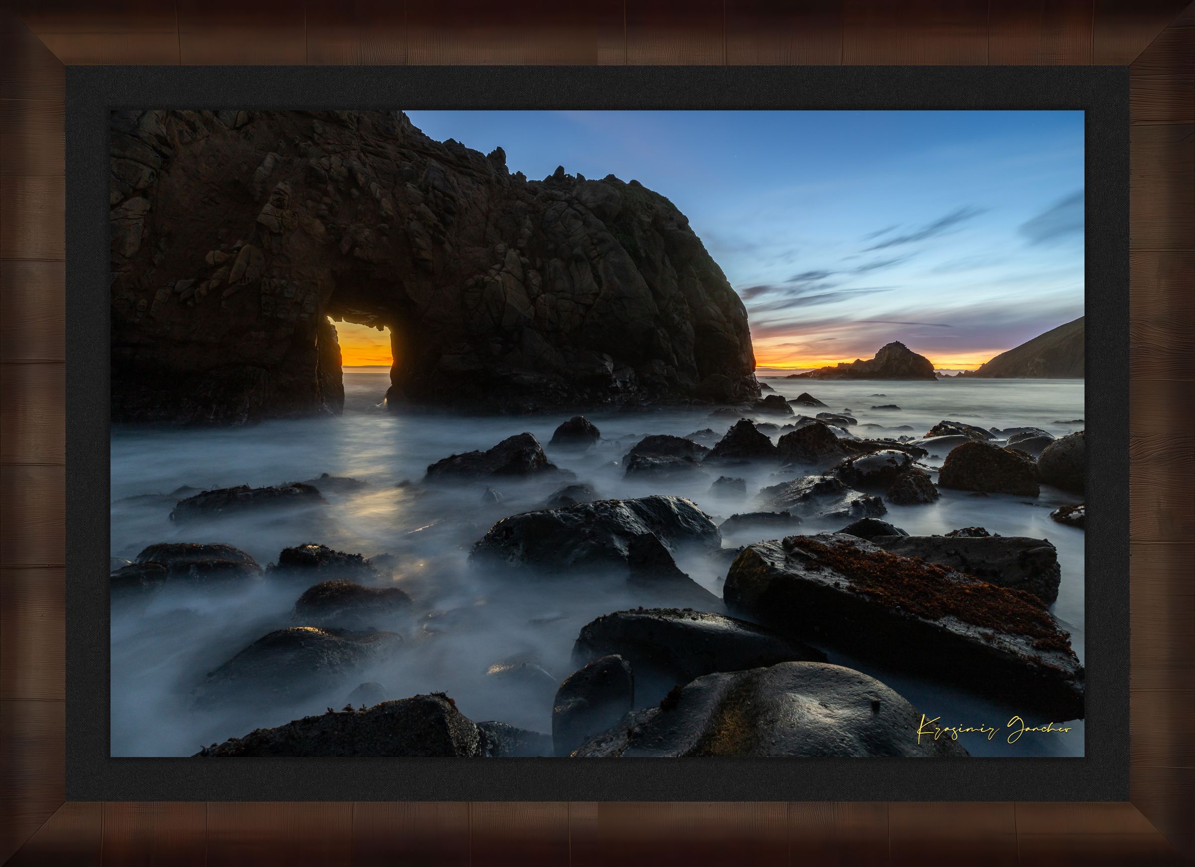 Natural arch structure with boulders and sea stack near Big Sur, California, lit by intense sunset rays through a stone opening. #Finish_Roma Cigar Leaf Frame & Dark Liner