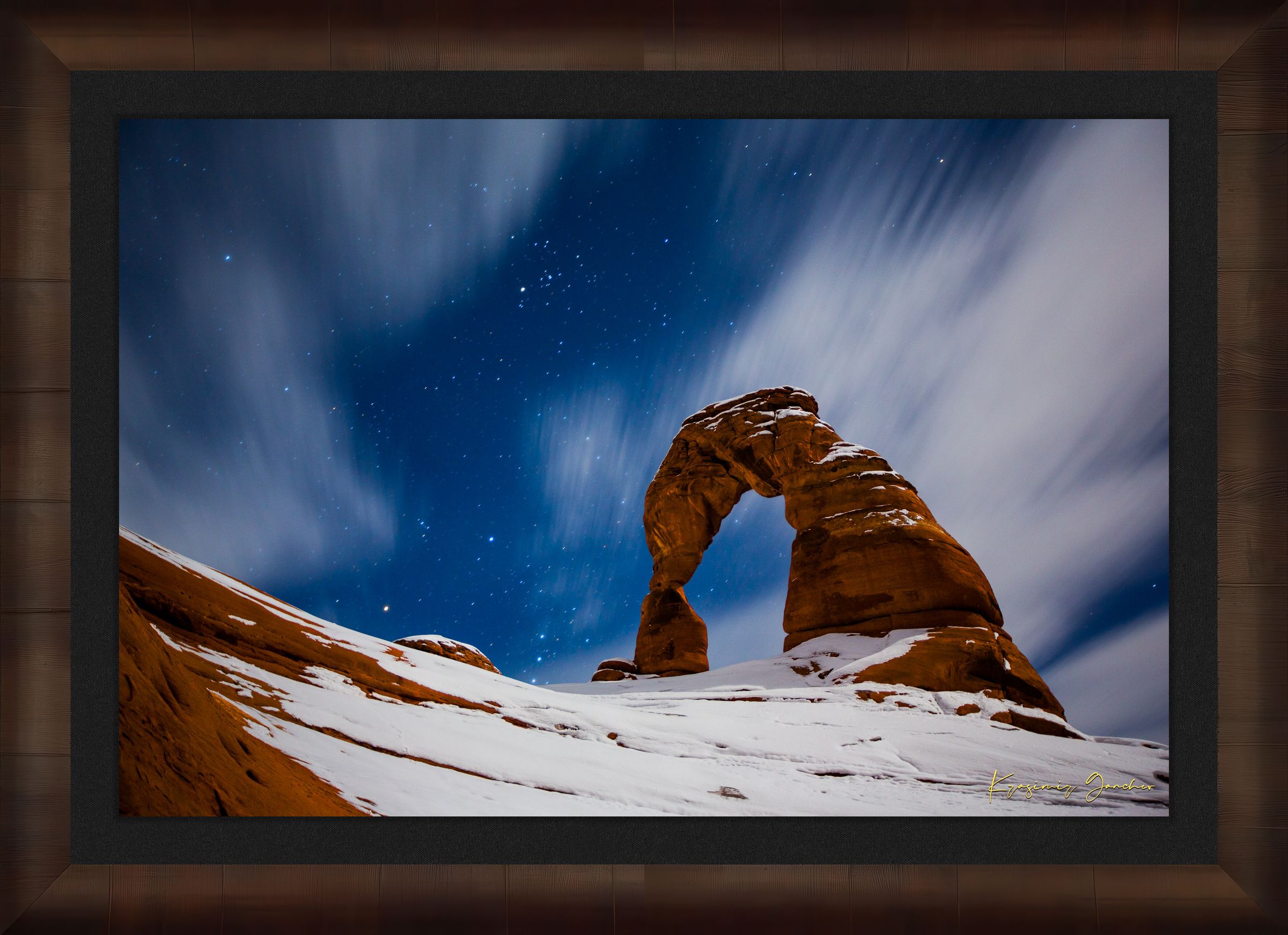 Iconic arch formation in Arches National Park captured during nighttime with starlight and light snow enhancing the serene desert scene. #Finish_Roma Cigar Leaf Frame & Dark Liner