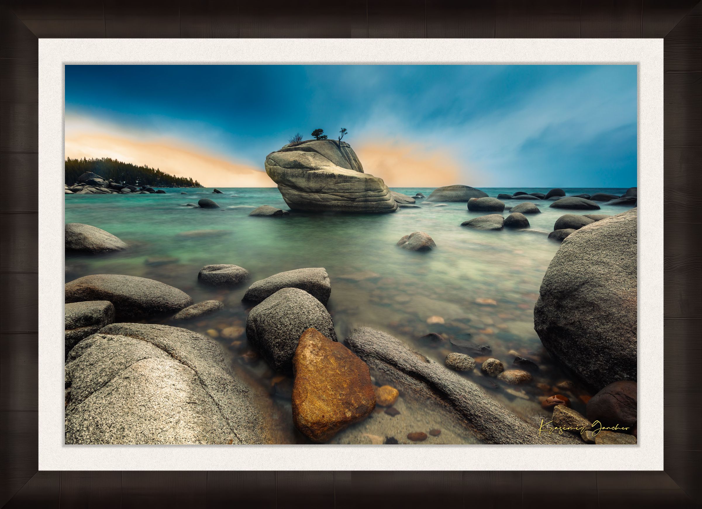 Bonsai Rock formation beside a calm lake in Lake Tahoe during sunset with gentle ripples and clouds. #Finish_Roma Dark Ash Frame & Bright Liner