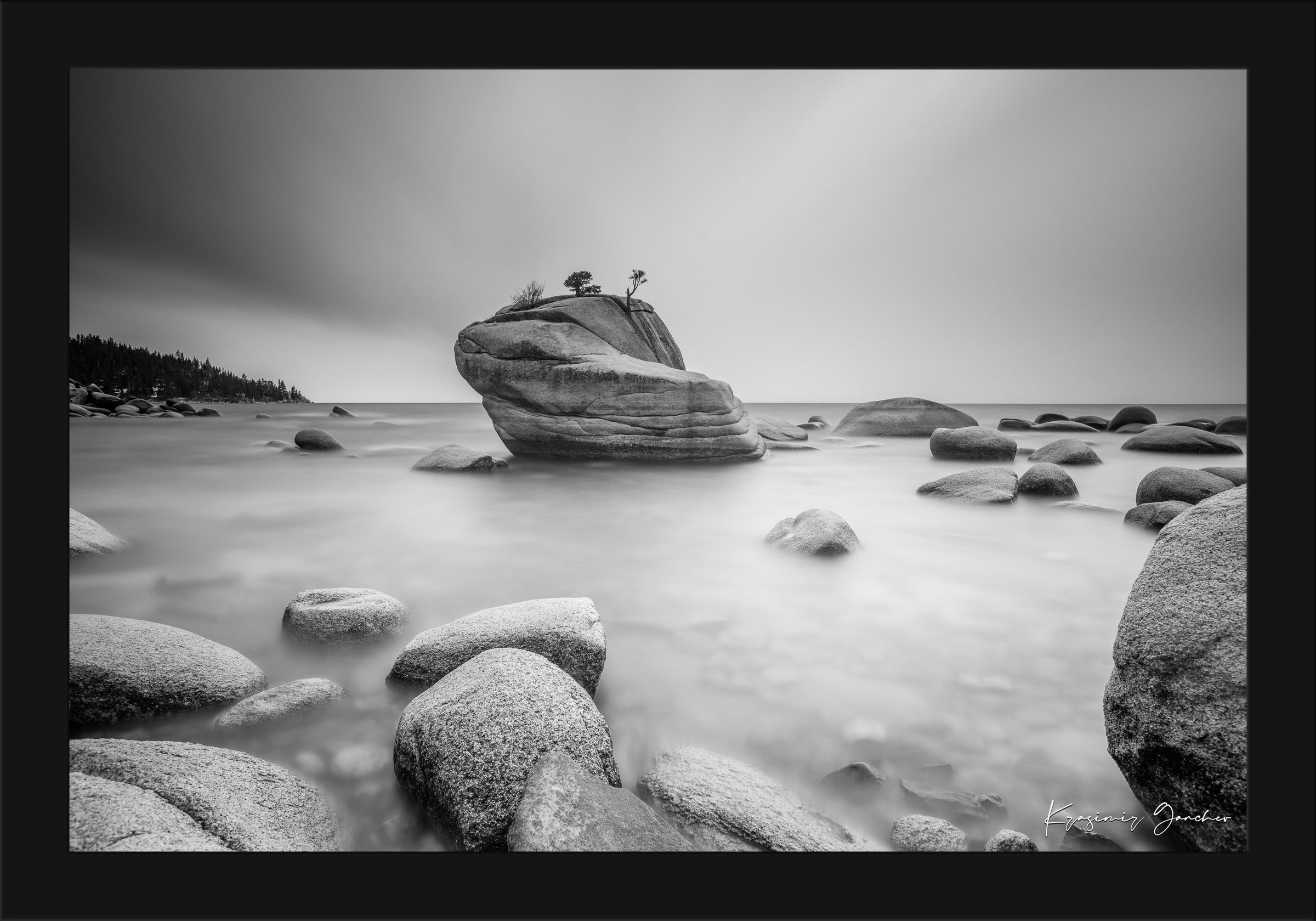 Large boulder named Bonsai Rock in Lake Tahoe surrounded by still, reflective waters under daytime light. #Finish_Roma Satin Black Frame
