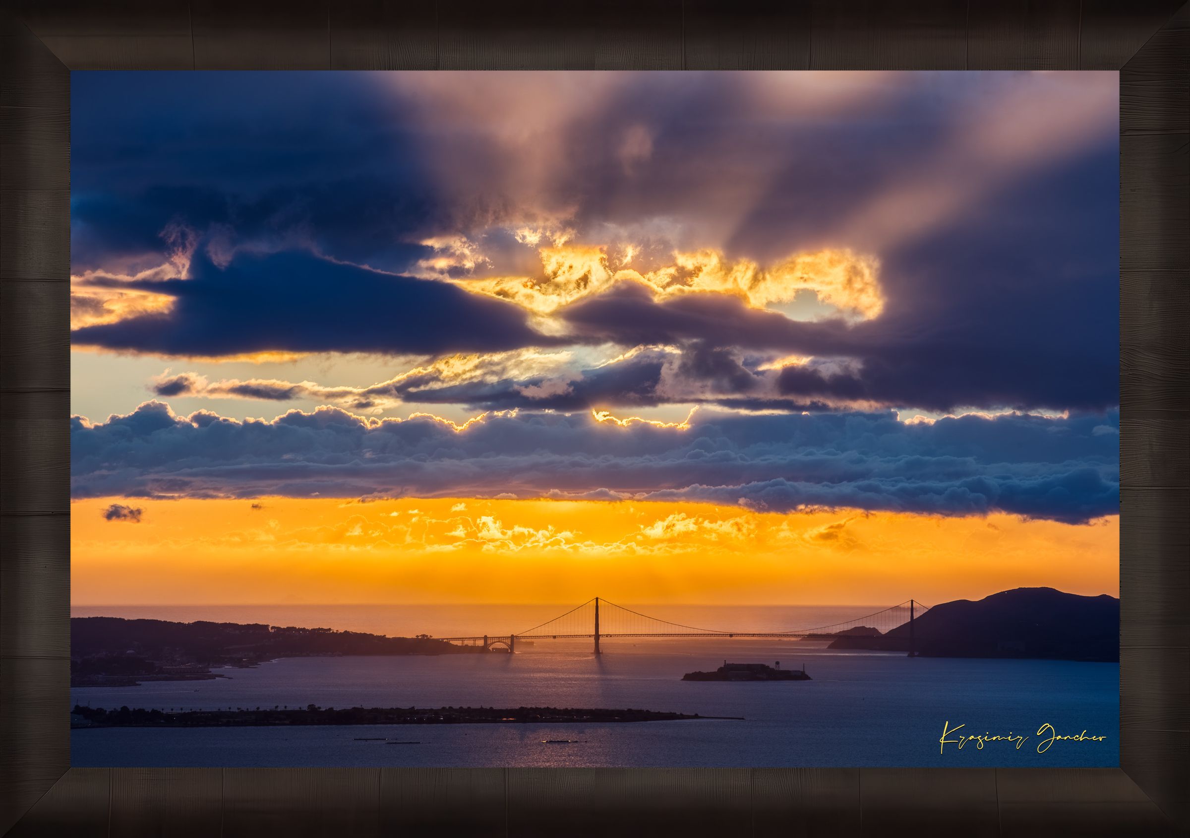 Golden Gate Bridge spanning a sunlit bay at sunset under layered stormy clouds, warm hues blending into cool sky tones. #Finish_Roma Dark Ash Frame