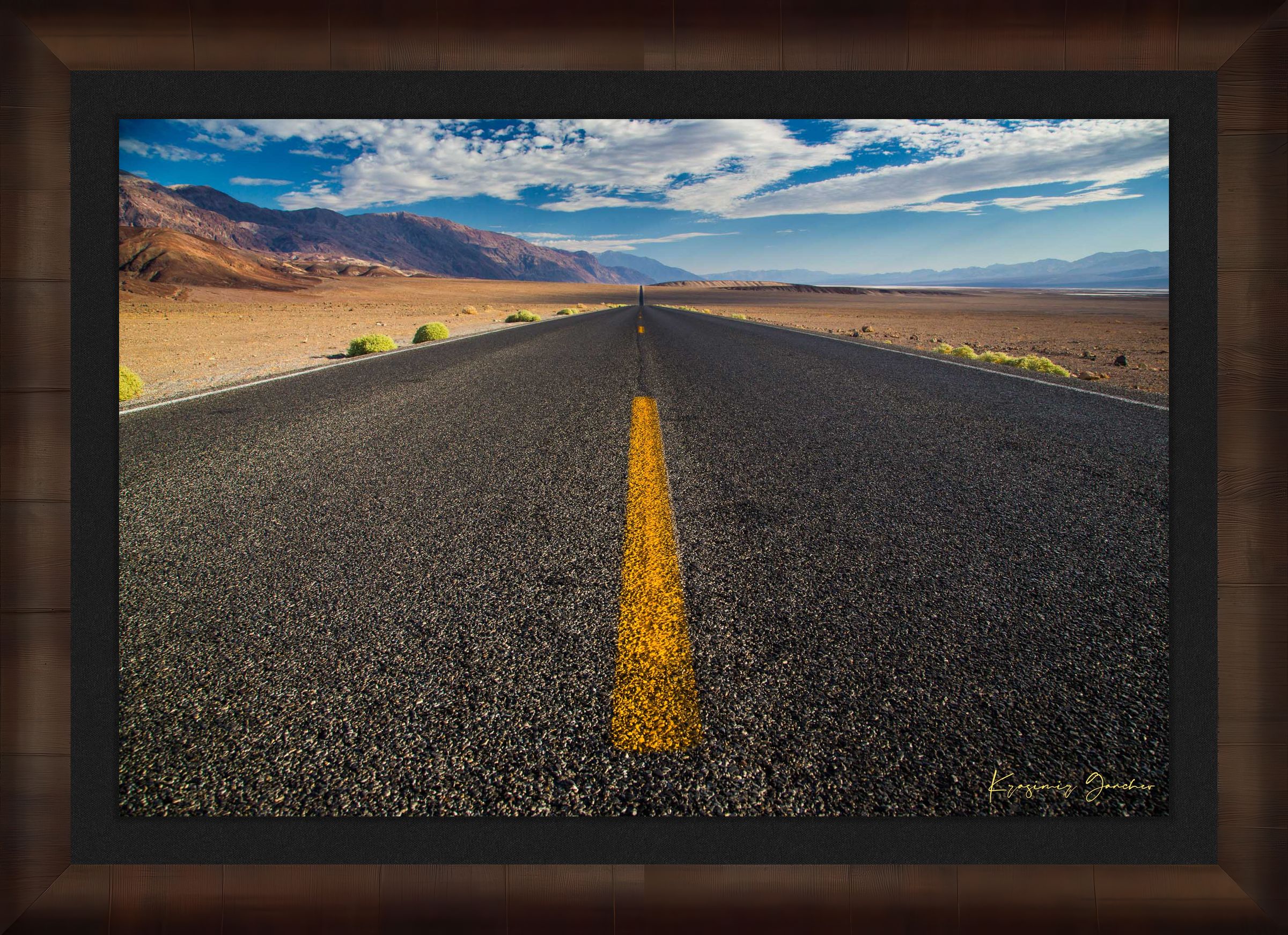 Straight desert road stretching into an open landscape of arid terrain in Death Valley National Park under overcast skies. #Finish_Roma Cigar Leaf Frame & Dark Liner