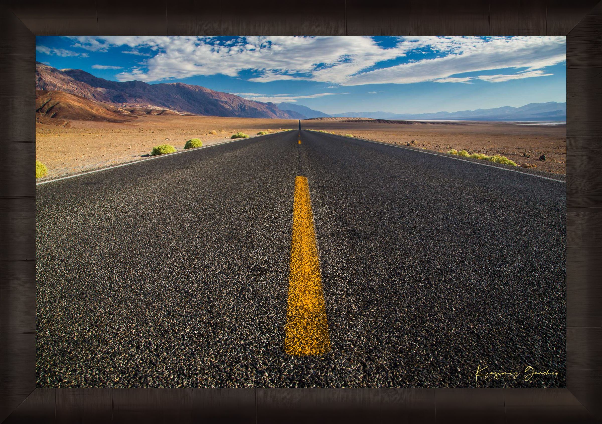 Straight desert road stretching into an open landscape of arid terrain in Death Valley National Park under overcast skies. #Finish_Roma Dark Ash Frame