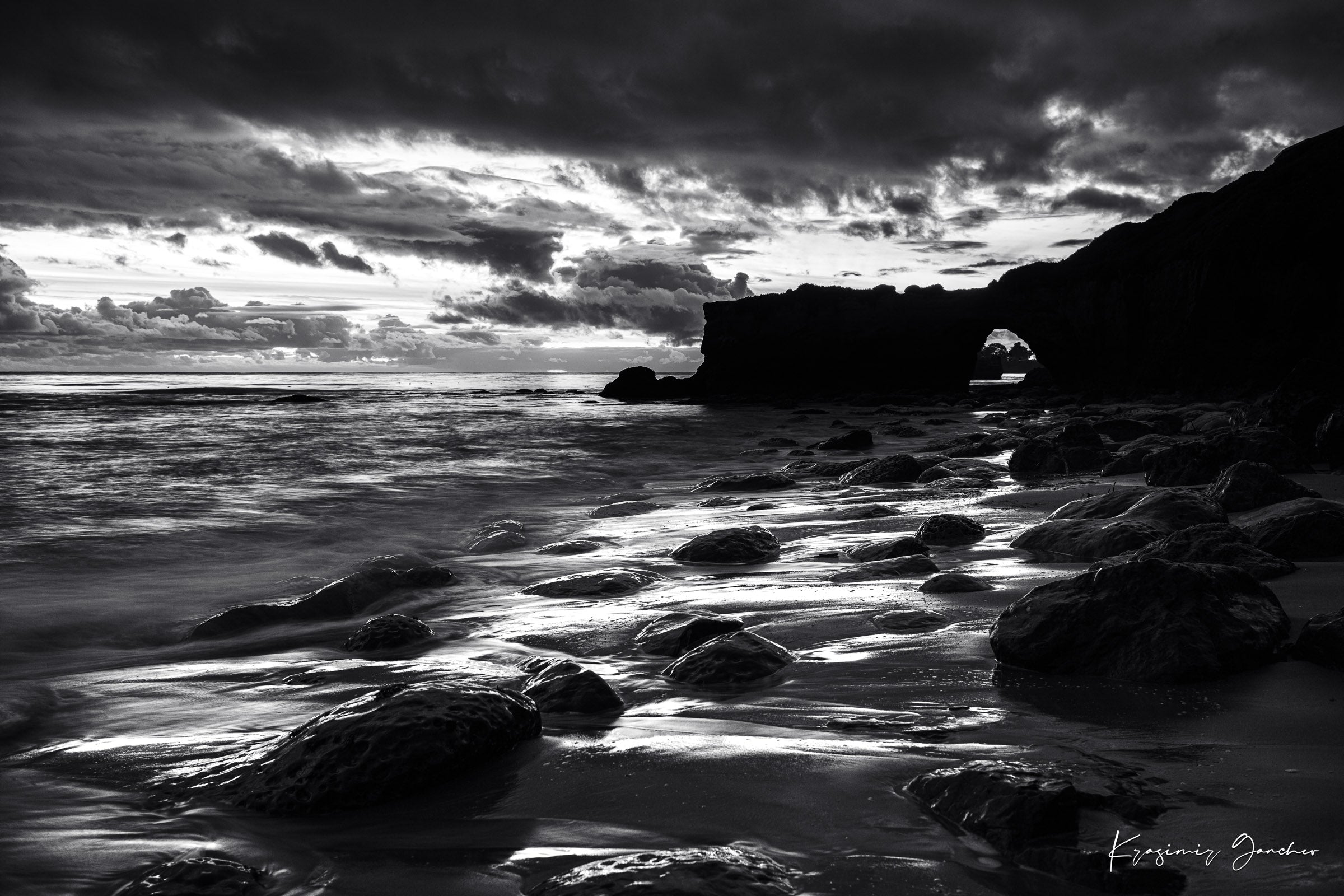 Black-and-white photograph showcasing a rock arch at Santa Cruz’s coastline during sunset with flowing waves. #Finish_Acrylic Recess