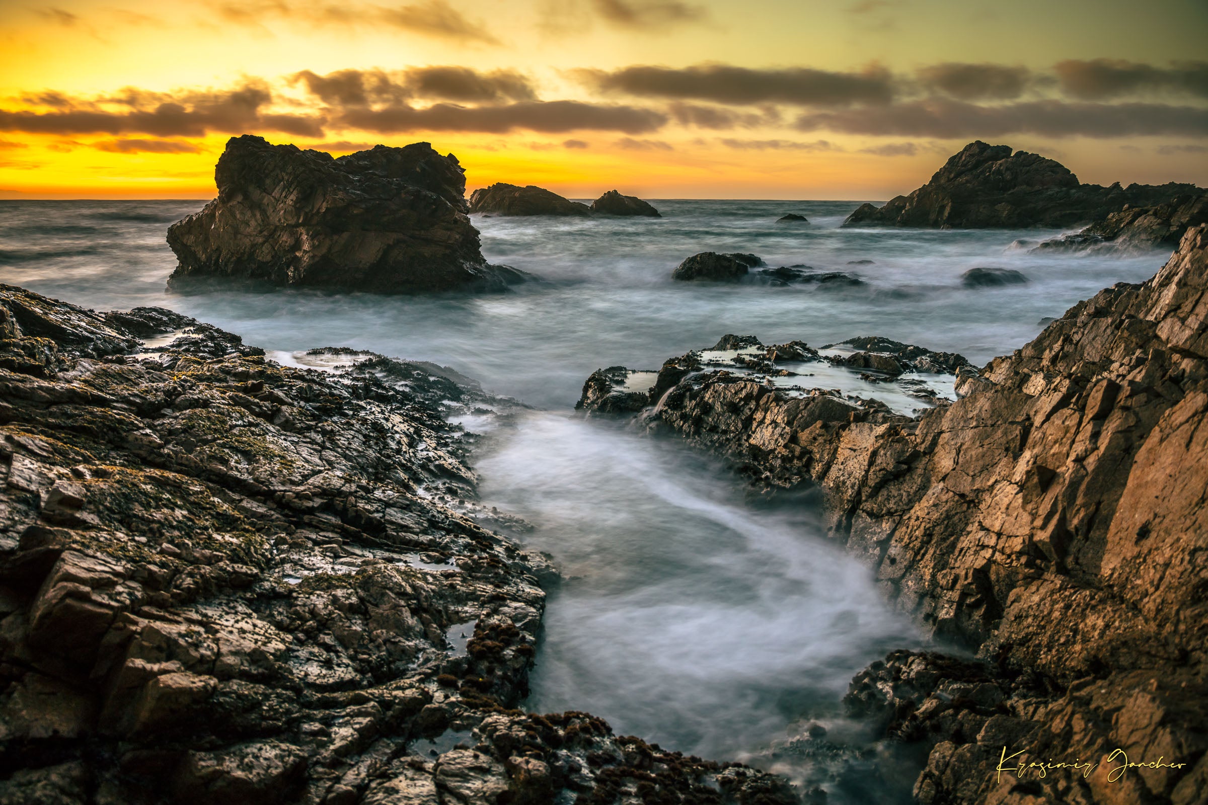 Jagged rocky cliffs along the Big Sur coast with rhythmic wave action, open ocean mist, clouds above, illuminated by late afternoon sunlight. #Finish_Acrylic Recess